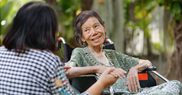 Elderly woman in wheelchair talking to her caregiver