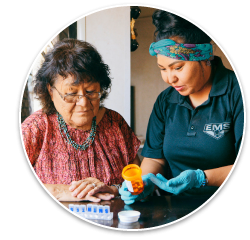 A community paramedic helping an elderly woman sort her medications into a pill box.